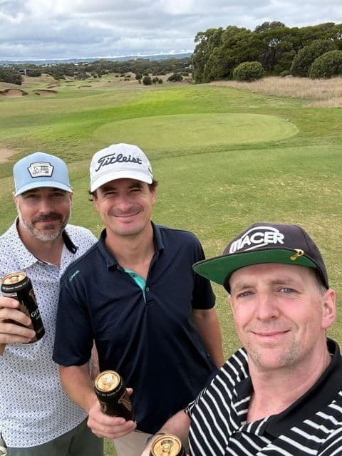 Three players with a beer beside the green