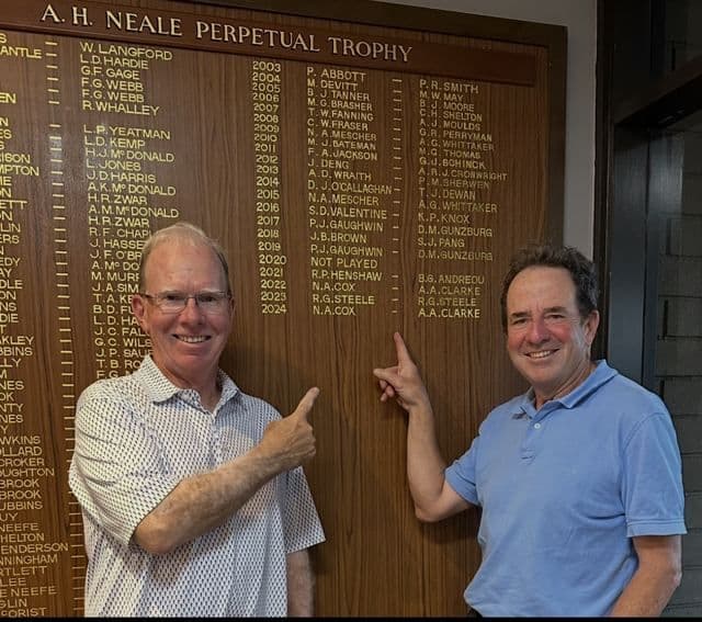 Two players pointing at the clubhouse honour board